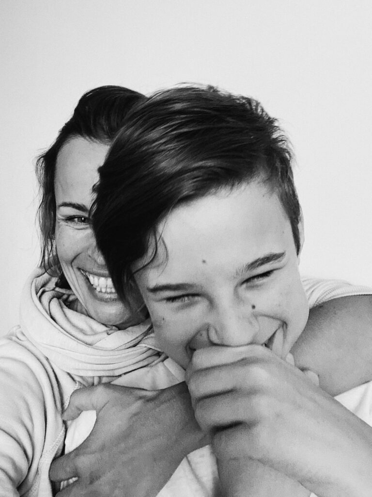 A heartwarming black and white capture of a mother and son sharing a joyful hug and laughter.